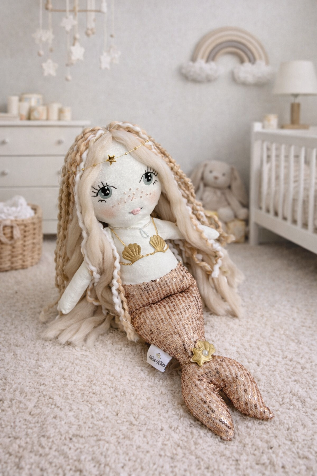 Handmade mermaid doll with hand-stitched face, yarn hair and soft fabric tail, styled in a neutral beach-inspired setting