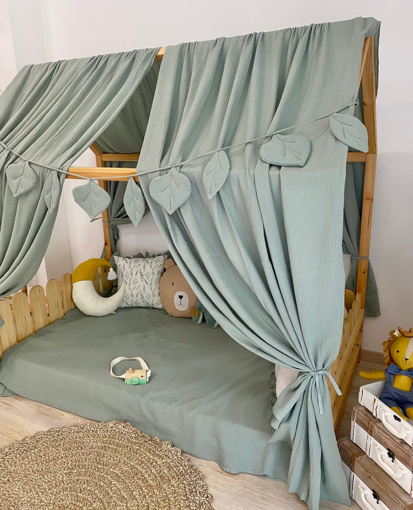 Sage green canopy over floor bed in kids room